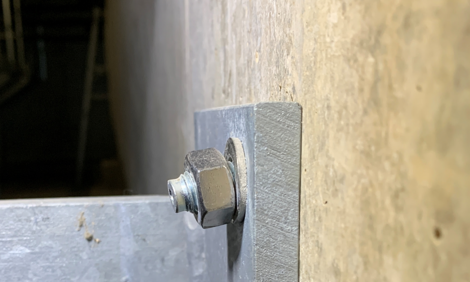 Ankerbefestigung im Stahlbau mit sichtbare Schiefstellung bzw. Montagefehler an einer Betonwand